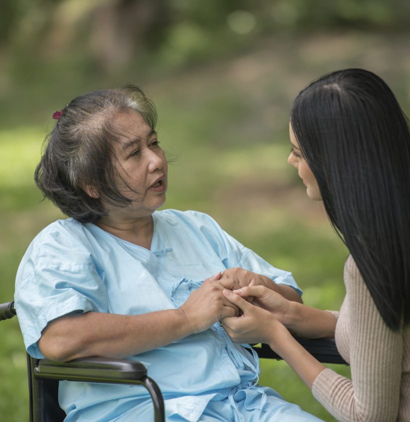 Granddaughter talking with her grandmother sitting on wheelchair, cheerful concept, happy family